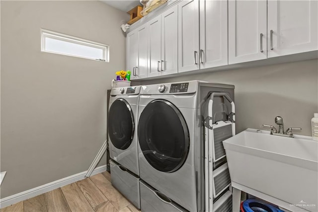 laundry room with washing machine and clothes dryer, sink, and cabinets