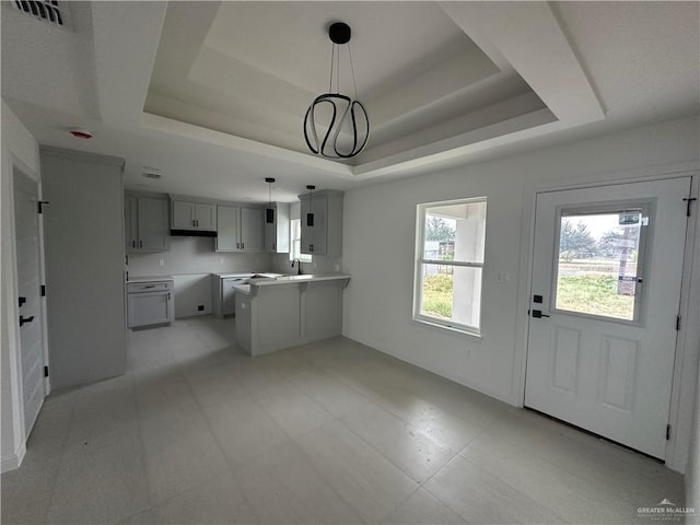 kitchen featuring gray cabinets, a raised ceiling, hanging light fixtures, and an inviting chandelier