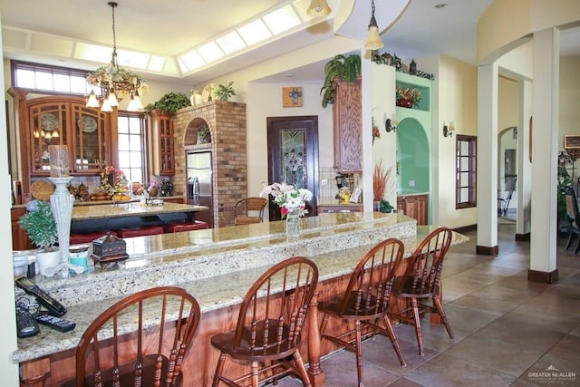 interior space featuring stainless steel refrigerator with ice dispenser, an inviting chandelier, hanging light fixtures, and light stone counters