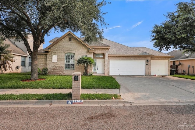 3902 Green Jay Dr, Mission, TX 78572 - view of front of home featuring a garage, driveway, brick siding, and a shingled roof