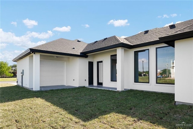 back of house featuring a lawn and a garage