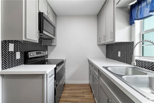 403 N 1st St, Donna, TX 78537 - kitchen with stainless steel appliances, a sink, gray cabinets, backsplash, and light countertops