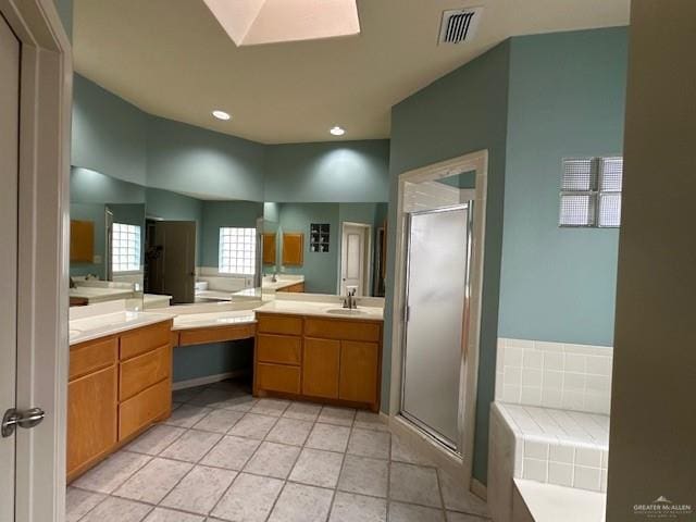 bathroom with a skylight, vanity, a shower with shower door, and tile patterned flooring