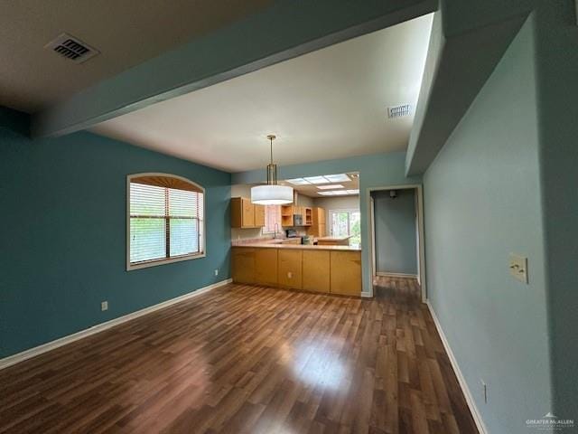 kitchen featuring beam ceiling, kitchen peninsula, dark hardwood / wood-style floors, and a healthy amount of sunlight