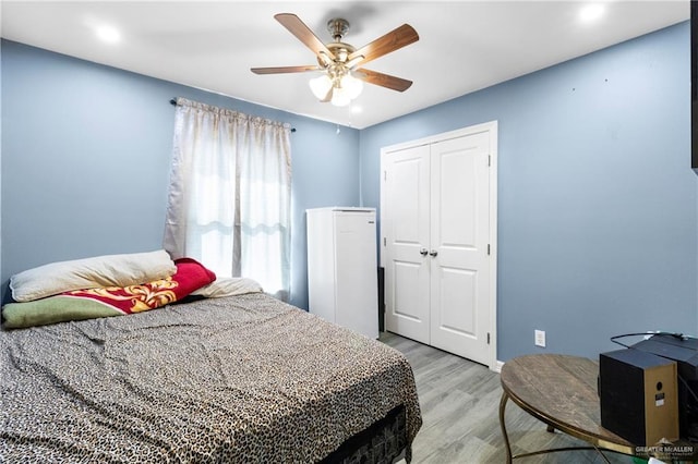 bedroom with a closet, light hardwood / wood-style floors, and ceiling fan