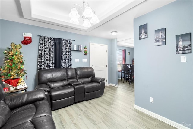 living room featuring hardwood / wood-style flooring, a raised ceiling, and a notable chandelier