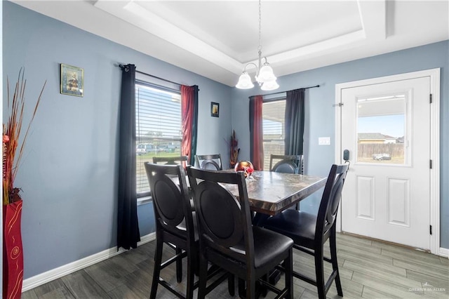 dining area featuring hardwood / wood-style flooring, a notable chandelier, and a tray ceiling