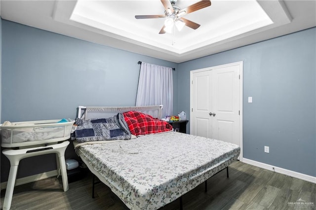 bedroom with ceiling fan, dark hardwood / wood-style flooring, and a raised ceiling