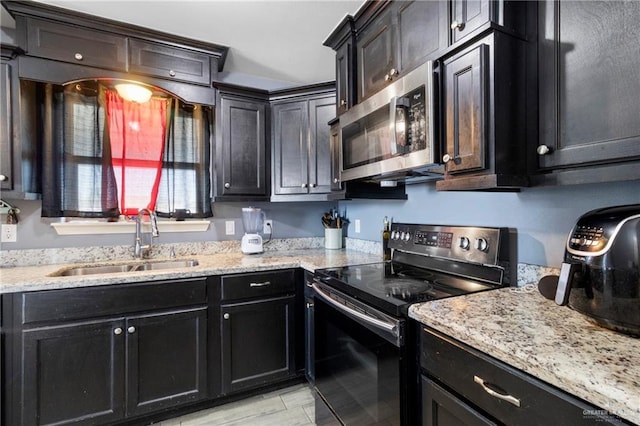 kitchen with light stone countertops, sink, stainless steel appliances, and light wood-type flooring