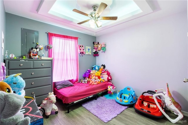 bedroom with hardwood / wood-style flooring, ceiling fan, and a tray ceiling