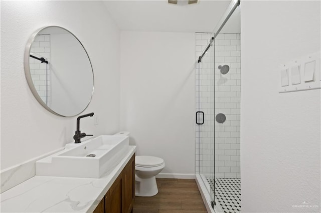 bathroom featuring wood-type flooring, vanity, toilet, and an enclosed shower