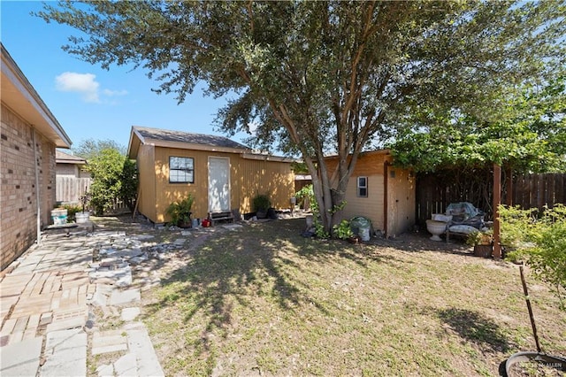 back of property featuring a lawn and a storage unit