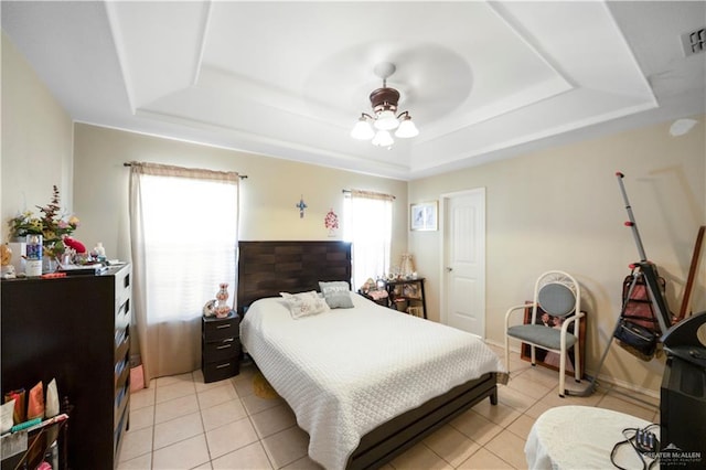 bedroom with ceiling fan, a raised ceiling, and light tile patterned floors