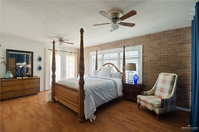 bedroom featuring hardwood / wood-style floors, ceiling fan, and brick wall