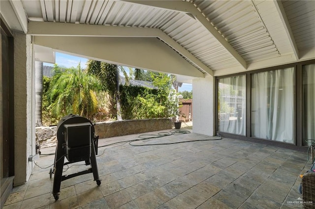 unfurnished sunroom featuring a healthy amount of sunlight and vaulted ceiling with beams