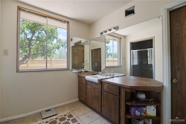 bathroom featuring tile patterned flooring, vanity, a healthy amount of sunlight, and walk in shower