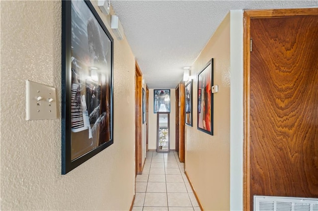 corridor featuring a textured ceiling and light tile patterned floors