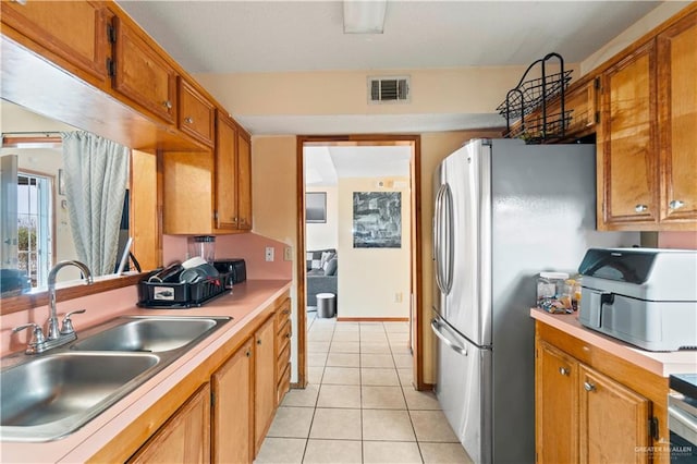 kitchen featuring stainless steel fridge, sink, and light tile patterned floors