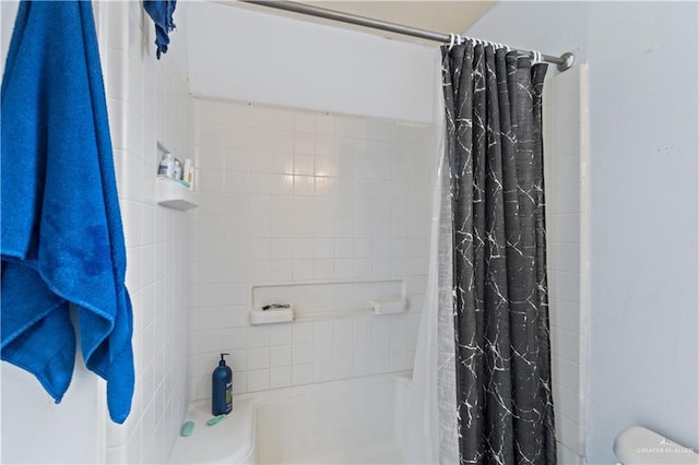 bathroom featuring shower / tub combo and toilet