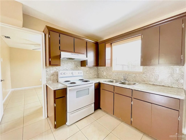 1411 Oak St, Weslaco, TX 78596 - kitchen with light tile patterned floors, under cabinet range hood, a sink, and white range with electric stovetop