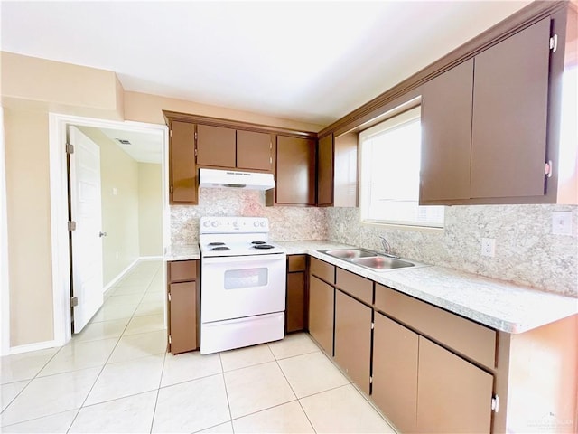 1411 Oak St, Weslaco, TX 78596 - kitchen with under cabinet range hood, light countertops, a sink, white electric range oven, and tasteful backsplash
