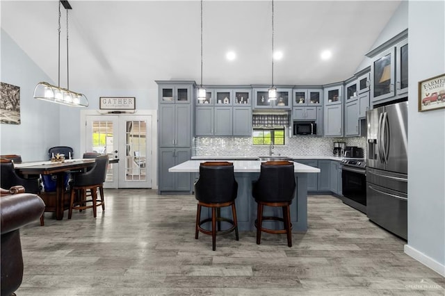 kitchen with decorative backsplash, light countertops, appliances with stainless steel finishes, and vaulted ceiling