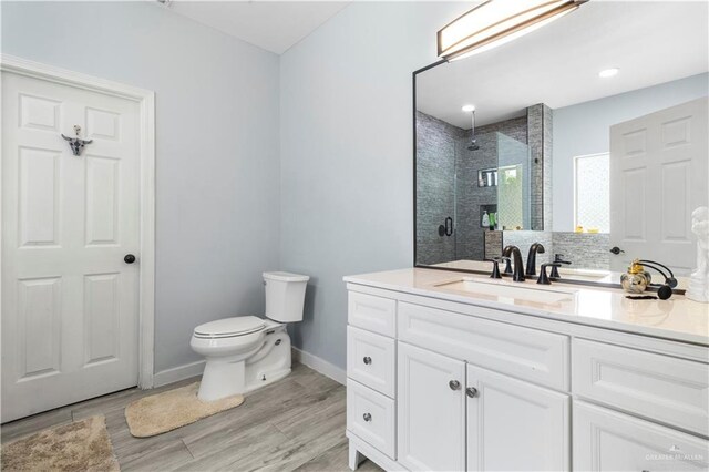 full bathroom with vanity, wood finished floors, baseboards, a stall shower, and toilet