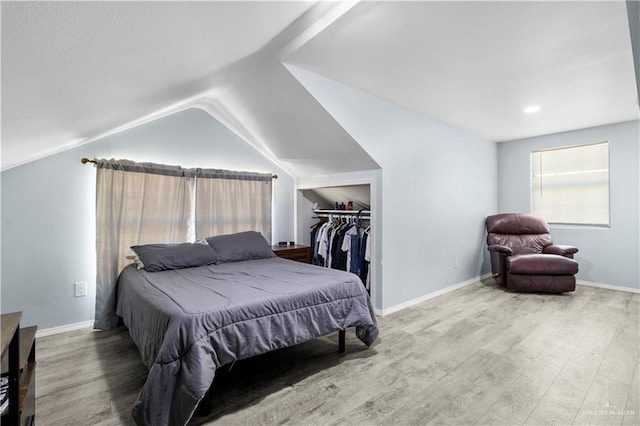 bedroom featuring baseboards, lofted ceiling, a closet, and wood finished floors