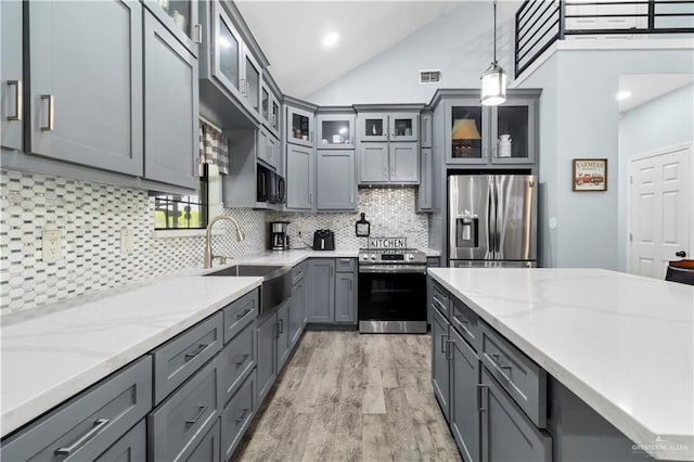 kitchen with visible vents, gray cabinetry, a sink, appliances with stainless steel finishes, and decorative light fixtures