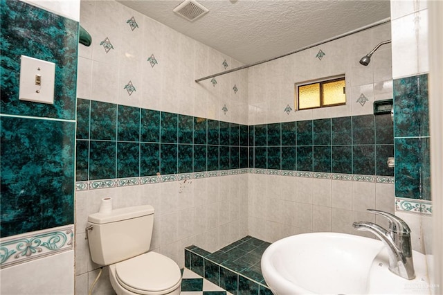 bathroom featuring sink, tile walls, a textured ceiling, and toilet