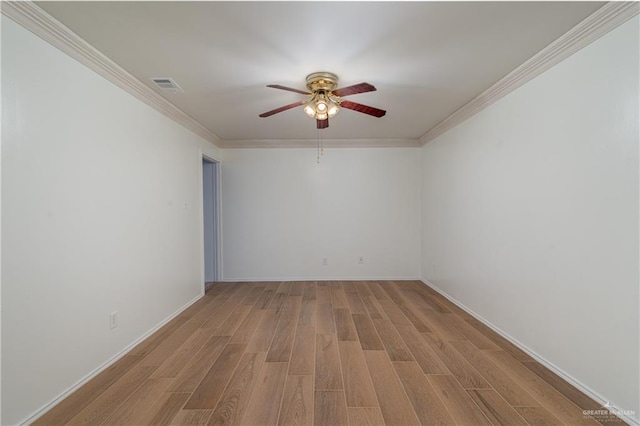 empty room with ornamental molding, visible vents, ceiling fan, and wood finished floors