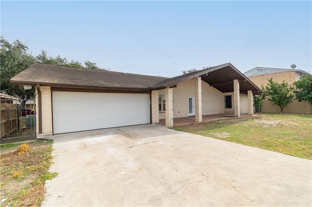 view of front of house with a garage, a front yard, fence, brick siding, and driveway