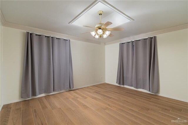 unfurnished room featuring light wood-style flooring, attic access, a ceiling fan, and crown molding