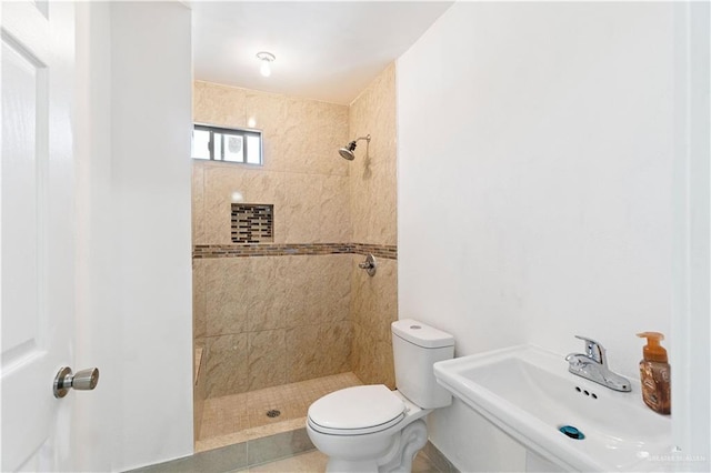 bathroom with tiled shower, toilet, and sink