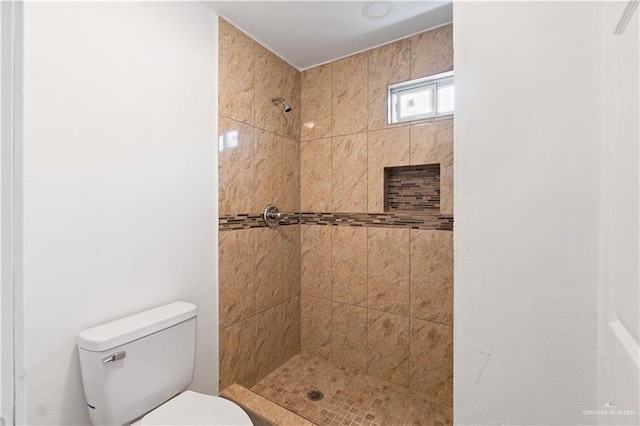 bathroom featuring toilet and a tile shower