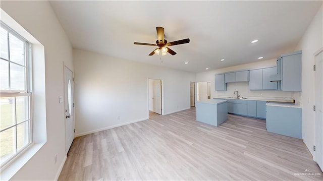 kitchen with plenty of natural light, a center island, light hardwood / wood-style floors, and sink