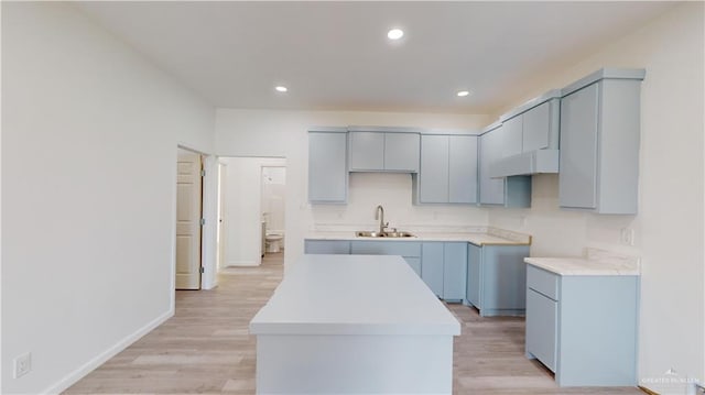 kitchen with sink, a kitchen island, and light hardwood / wood-style flooring