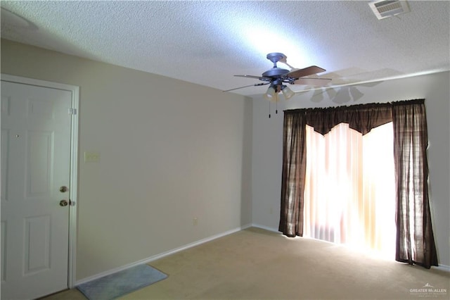 unfurnished room with a textured ceiling, light colored carpet, and ceiling fan