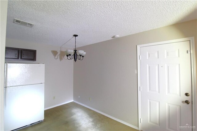 unfurnished dining area with a chandelier, a textured ceiling, and carpet flooring