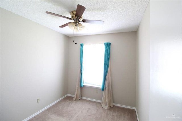 empty room with ceiling fan, light colored carpet, and a textured ceiling