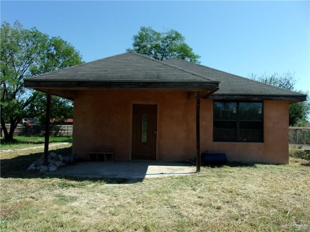 rear view of house with a patio and a lawn