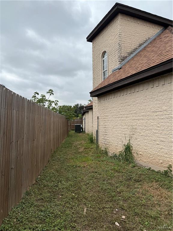 view of side of home with a lawn and cooling unit