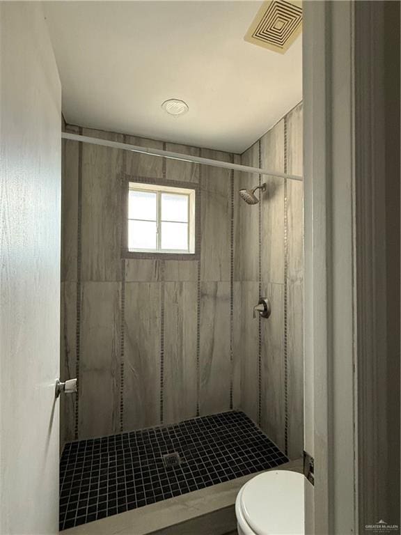 bathroom with a tile shower and toilet