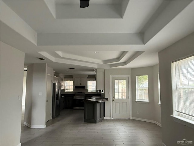 kitchen with a tray ceiling, a wealth of natural light, and range with electric stovetop