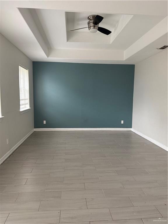 unfurnished room featuring light wood-type flooring, a raised ceiling, and ceiling fan