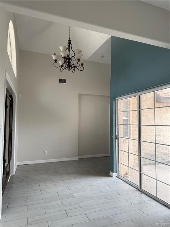 unfurnished dining area featuring high vaulted ceiling, a chandelier, and light hardwood / wood-style floors