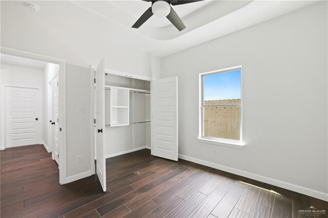 unfurnished bedroom with a closet, a raised ceiling, wood finished floors, baseboards, and ceiling fan