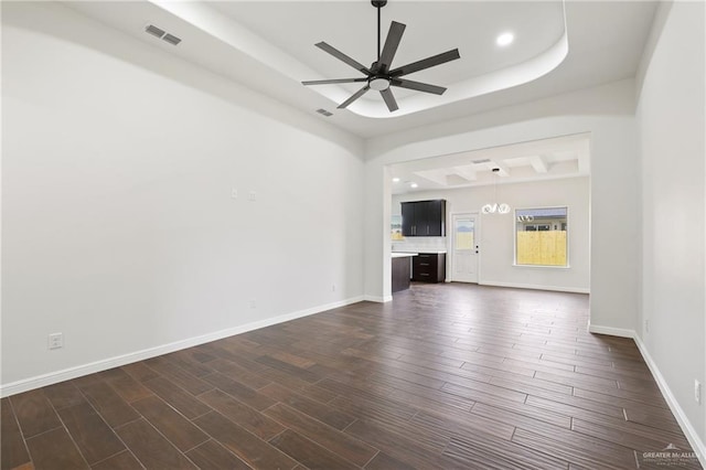 unfurnished living room featuring a tray ceiling, baseboards, visible vents, ceiling fan, and dark wood-type flooring