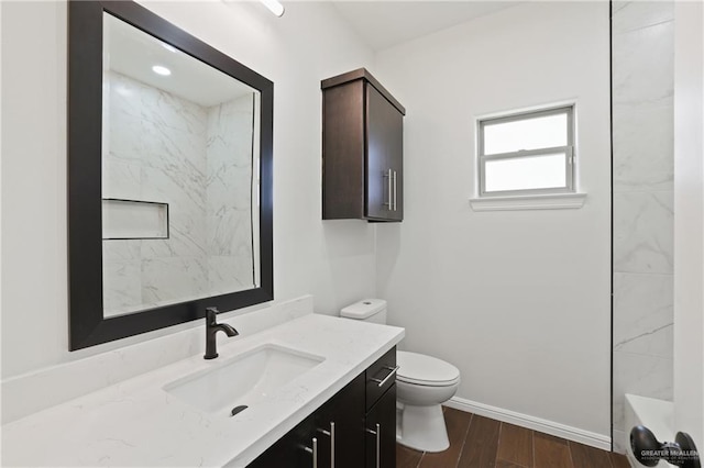 bathroom featuring toilet, wood finished floors, baseboards, and vanity