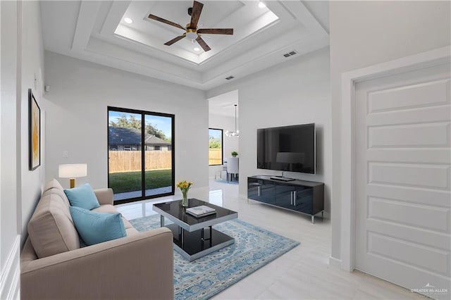 living area featuring visible vents, a raised ceiling, a high ceiling, and ceiling fan